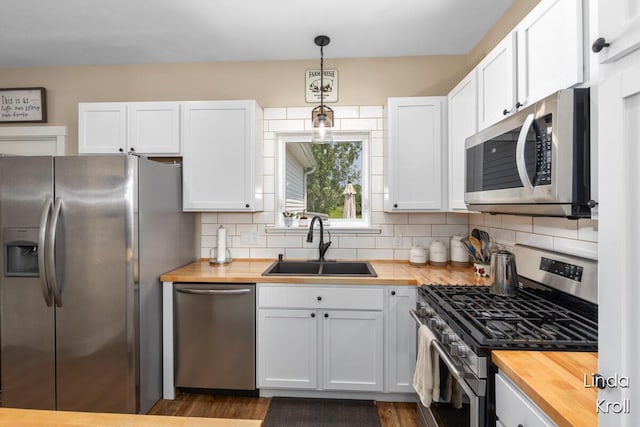 195 Liberty St NW, Sparta, MI 49345 - kitchen with appliances with stainless steel finishes, butcher block counters, white cabinetry, tasteful backsplash, and decorative light fixtures