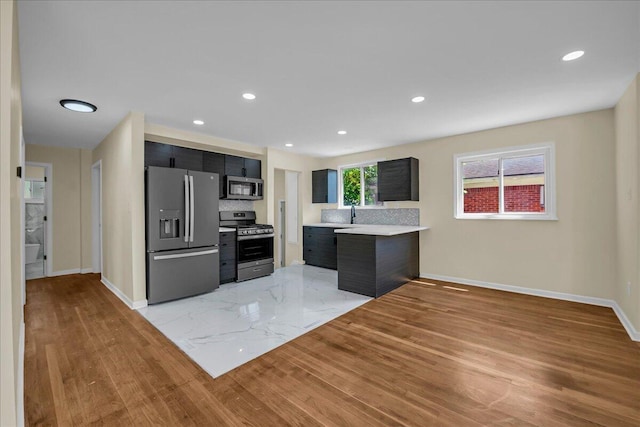 20232 Braile St, Detroit, MI 48219 - kitchen featuring stainless steel appliances, light wood finished floors, light countertops, dark cabinets, and tasteful backsplash