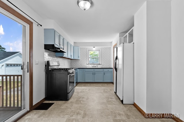 641 52nd St SE, Grand Rapids, MI 49548 - kitchen with stainless steel range with gas stovetop, freestanding refrigerator, under cabinet range hood, blue cabinetry, and backsplash