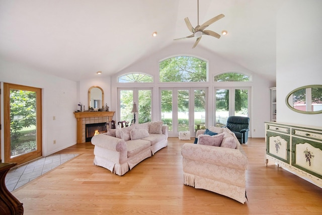 6990 Kennedy Rd, Munith, MI 49259 - living area featuring healthy amount of natural light, a tiled fireplace, a ceiling fan, wood finished floors, and lofted ceiling