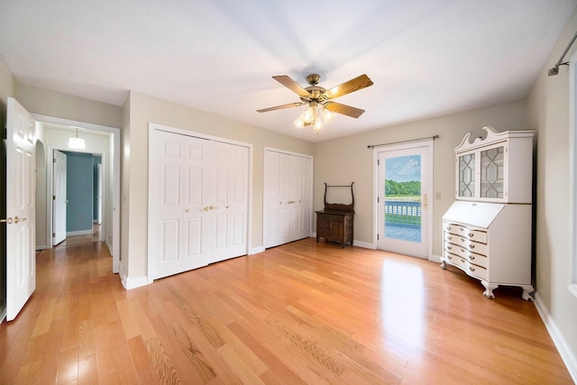 6990 Kennedy Rd, Munith, MI 49259 - unfurnished bedroom with access to outside, two closets, light wood-style floors, and a ceiling fan