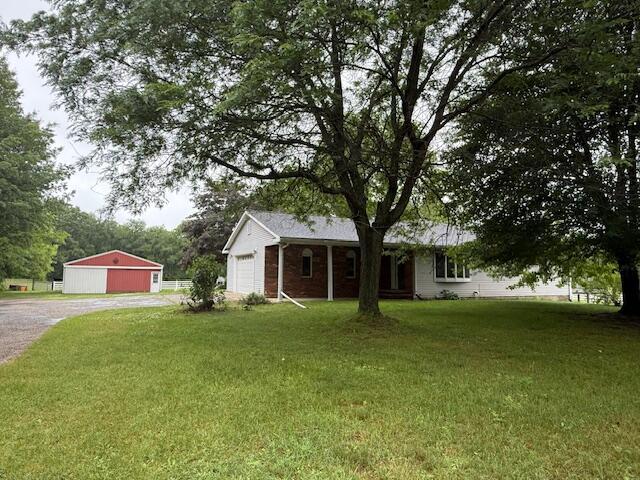 6990 Kennedy Rd, Munith, MI 49259 - ranch-style home featuring a front lawn, gravel driveway, and an attached garage