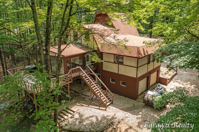 9550 Pere Marquette Dr, Stanwood, MI 49346 - back of house with roof with shingles, stairs, a sunroom, an attached garage, and a deck