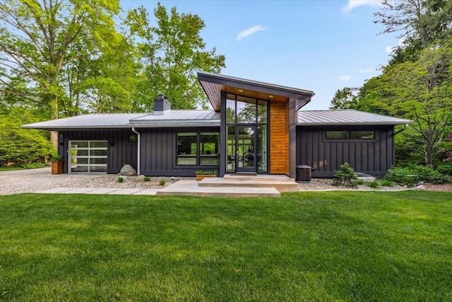 16128 Walnut Ct, Three Oaks, MI 49128 - back of property with board and batten siding, an attached garage, a chimney, and a yard