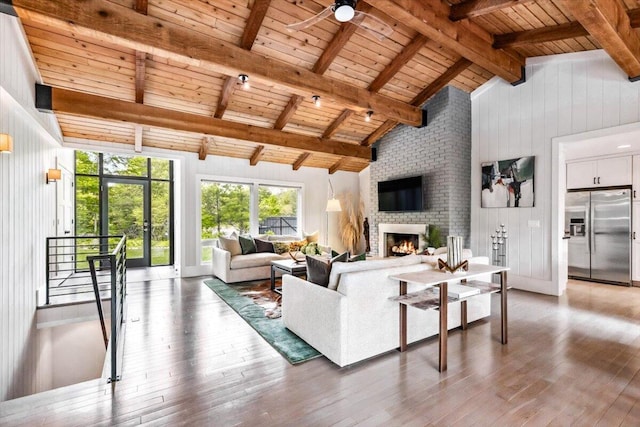 16128 Walnut Ct, Three Oaks, MI 49128 - living area featuring a wooden ceiling with exposed beams, wood-type flooring, ceiling fan, a brick fireplace, and wood walls