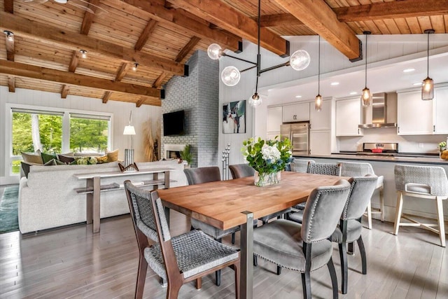 16128 Walnut Ct, Three Oaks, MI 49128 - dining area featuring a wood ceiling with exposed beams, hardwood / wood-style flooring, a fireplace, and high vaulted ceiling