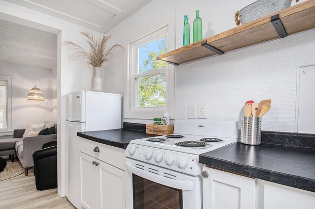 501 Sherwood Ave, Three Oaks, MI 49128 - kitchen with white appliances, dark countertops, white cabinets, light wood-style floors, and open shelves