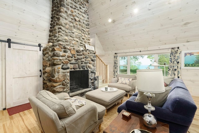 2821 Lakeshore Rd, Lexington, MI 48450 - living room featuring a high ceiling, light wood-style flooring, a barn door, wooden walls, and a stone fireplace