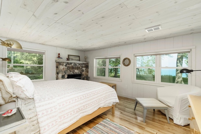 2821 Lakeshore Rd, Lexington, MI 48450 - bedroom with light wood finished floors, wooden ceiling, and a stone fireplace