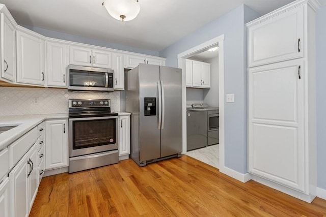 450 Carefree Ct, Niles, MI 49120 - kitchen with stainless steel appliances, washer and dryer, white cabinetry, and light wood-style floors