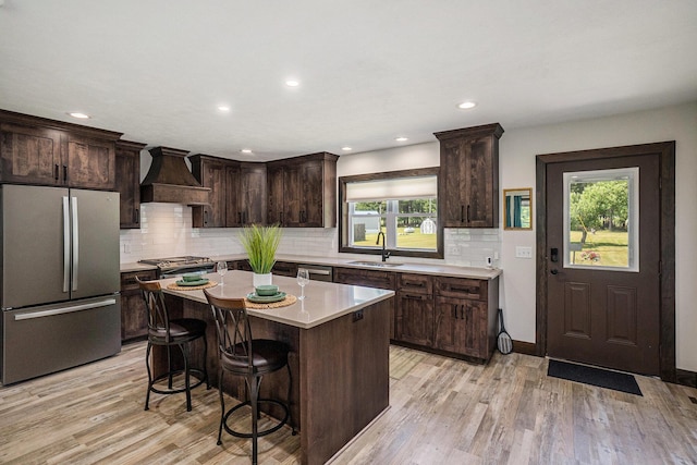 2480 S 148th Ave, Hesperia, MI 49421 - kitchen with appliances with stainless steel finishes, custom exhaust hood, dark brown cabinets, light countertops, and a kitchen breakfast bar