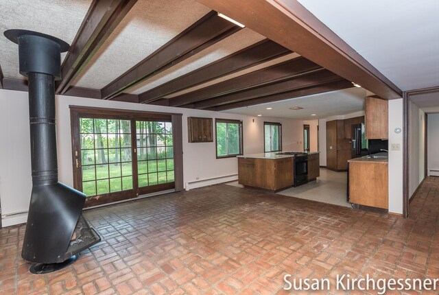 1129 Idema Dr SE, Grand Rapids, MI 49506 - kitchen with a baseboard radiator, black gas range oven, a center island, a wood stove, and open floor plan