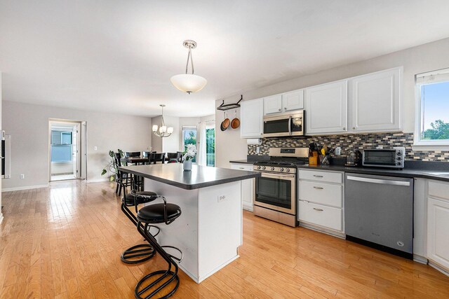 1735 Savannah Ln, Ypsilanti, MI 48198 - kitchen with appliances with stainless steel finishes, dark countertops, backsplash, a kitchen breakfast bar, and white cabinets