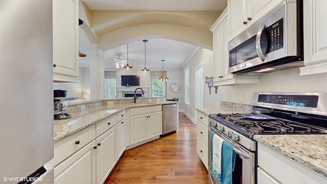 120 S Kenzie St, New Buffalo, MI 49117 - kitchen with appliances with stainless steel finishes, arched walkways, a ceiling fan, light wood-style flooring, and crown molding