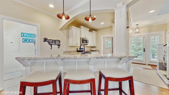 120 S Kenzie St, New Buffalo, MI 49117 - kitchen featuring stainless steel microwave, light stone counters, decorative light fixtures, crown molding, and a kitchen bar