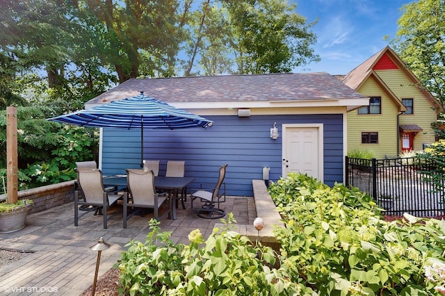 120 S Kenzie St, New Buffalo, MI 49117 - rear view of house featuring a patio, roof with shingles, outdoor dining space, and an outbuilding