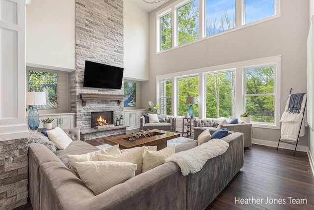 8069 Ella Terrace Ct, Rockford, MI 49341 - living area with a towering ceiling, plenty of natural light, a stone fireplace, and dark wood-style flooring