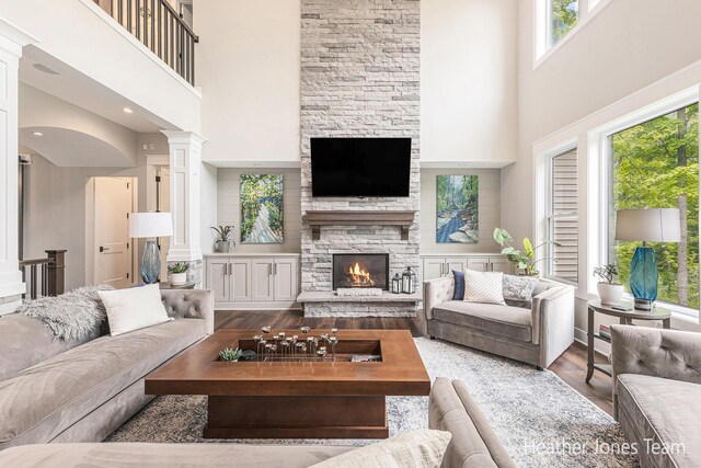 8069 Ella Terrace Ct, Rockford, MI 49341 - living area featuring a towering ceiling, wood finished floors, a fireplace, and ornate columns