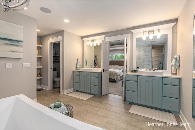 8069 Ella Terrace Ct, Rockford, MI 49341 - ensuite bathroom featuring a chandelier, vanity, a freestanding tub, wood finish floors, and recessed lighting