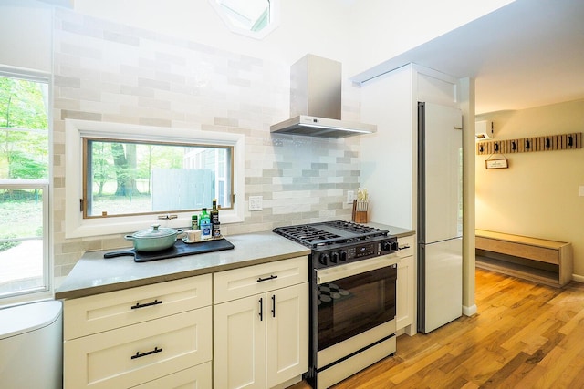 6670 Ravenswood Ave, Sawyer, MI 49125 - kitchen featuring wall chimney exhaust hood, range with gas stovetop, white refrigerator, and tasteful backsplash