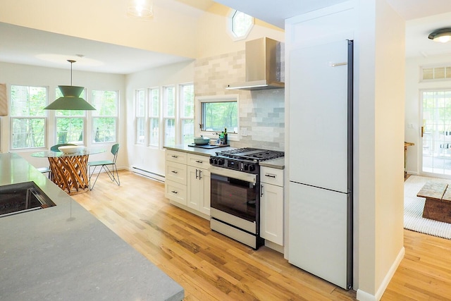 6670 Ravenswood Ave, Sawyer, MI 49125 - kitchen with freestanding refrigerator, gas range oven, light wood finished floors, baseboard heating, and decorative backsplash