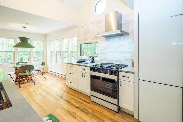 6670 Ravenswood Ave, Sawyer, MI 49125 - kitchen featuring gas stove, wall chimney exhaust hood, freestanding refrigerator, white cabinets, and light wood-style flooring