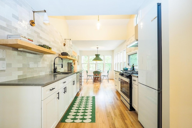 6670 Ravenswood Ave, Sawyer, MI 49125 - kitchen with stainless steel appliances, tasteful backsplash, light wood-style flooring, dark countertops, and white cabinetry