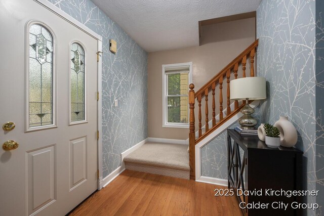 1052 Santa Cruz Dr SE, Grand Rapids, MI 49506 - entrance foyer featuring wallpapered walls, stairway, wood finished floors, an accent wall, and a textured ceiling