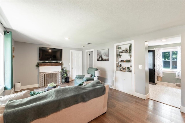 211 W S St, Grand Ledge, MI 48837 - living room featuring wood finished floors, a fireplace, built in features, and a textured ceiling