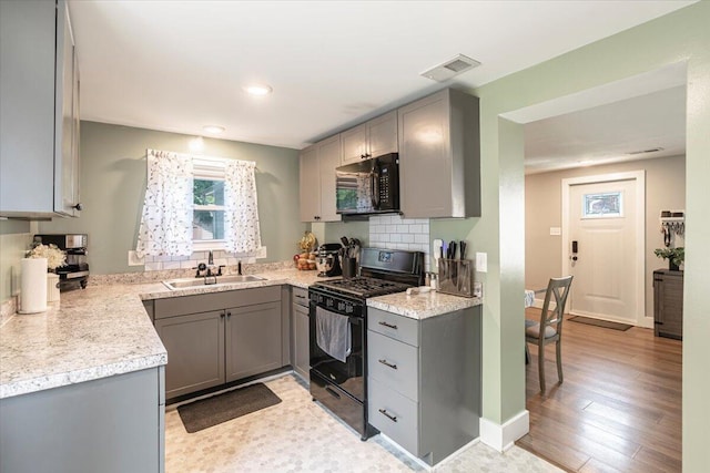 211 W S St, Grand Ledge, MI 48837 - kitchen featuring black appliances, gray cabinetry, light countertops, tasteful backsplash, and light wood-style flooring