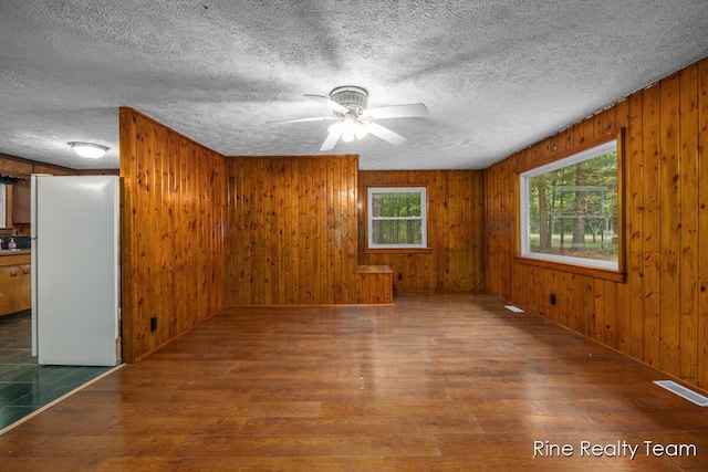 757 E Sidney Rd, Stanton, MI 48888 - spare room featuring wood finished floors, wood walls, a ceiling fan, and a textured ceiling