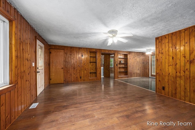 757 E Sidney Rd, Stanton, MI 48888 - spare room with wood walls, wood finished floors, a textured ceiling, and ceiling fan