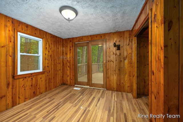 757 E Sidney Rd, Stanton, MI 48888 - unfurnished room featuring light wood finished floors, wooden walls, and a textured ceiling