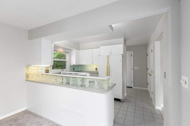 2647 Manitoba Ct NE, Grand Rapids, MI 49525 - kitchen featuring freestanding refrigerator, a peninsula, white cabinetry, and light tile patterned flooring
