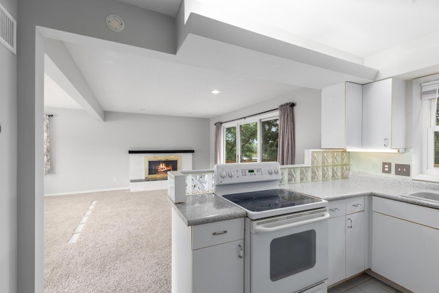 2647 Manitoba Ct NE, Grand Rapids, MI 49525 - kitchen featuring white electric stove, a peninsula, a lit fireplace, open floor plan, and white cabinetry