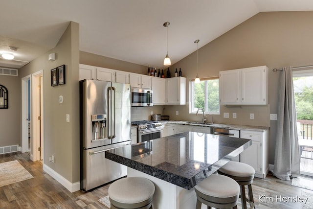 4284 Ives Farm Ln NE, Cedar Springs, MI 49319 - kitchen with appliances with stainless steel finishes, a breakfast bar, light wood-type flooring, white cabinetry, and hanging light fixtures