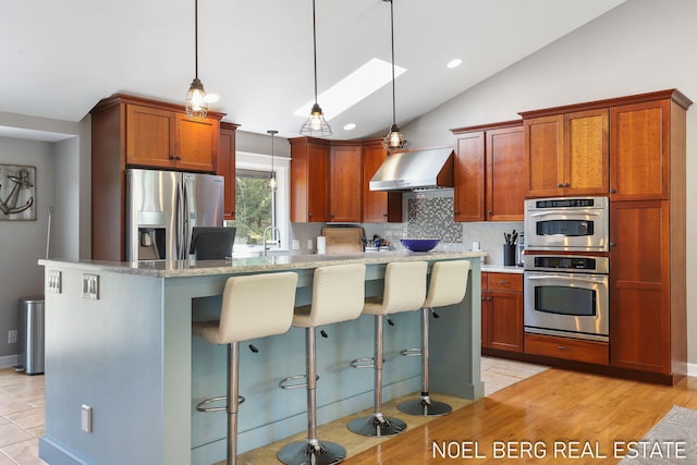 16093 Harbor Point Dr, Spring Lake, MI 49456 - kitchen featuring stainless steel appliances, wall chimney exhaust hood, lofted ceiling, backsplash, and a kitchen bar