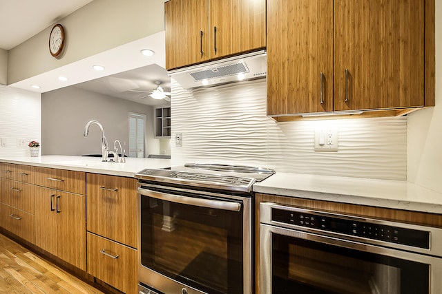 22 Haverhill Ct, Ann Arbor, MI 48105 - kitchen featuring stainless steel appliances, range hood, a ceiling fan, light wood-style flooring, and brown cabinetry