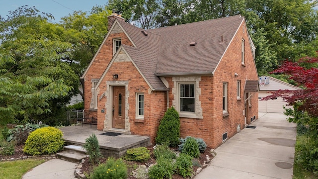 22836 Wellington St, Dearborn, MI 48124 - tudor house with brick siding, an outdoor structure, a chimney, a shingled roof, and a detached garage