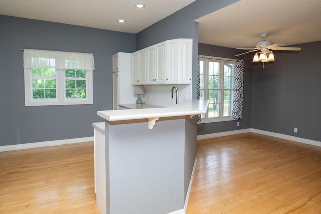 5412 Blackberry Ln, Coloma, MI 49038 - kitchen featuring light wood-type flooring, white cabinets, light countertops, a breakfast bar, and ceiling fan