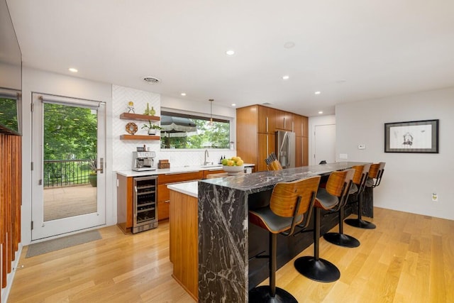 4330 Eastgate Dr, Ann Arbor, MI 48103 - kitchen featuring wine cooler, stainless steel fridge with ice dispenser, brown cabinetry, a kitchen breakfast bar, and decorative backsplash
