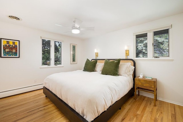 4330 Eastgate Dr, Ann Arbor, MI 48103 - bedroom featuring multiple windows, light wood-style flooring, a baseboard heating unit, and a ceiling fan