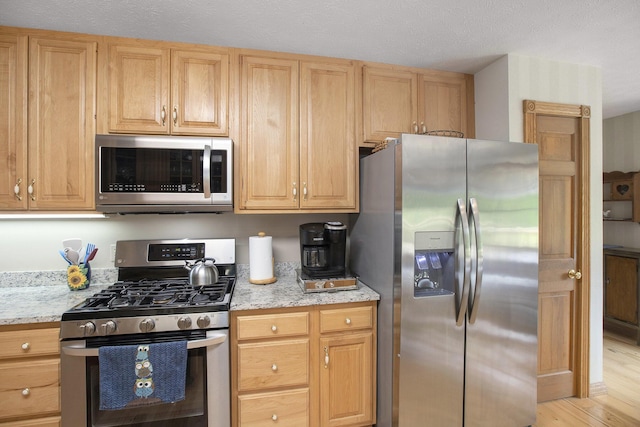 7272 E M 113, Kingsley, MI 49649 - kitchen featuring stainless steel appliances, light stone counters, light wood finished floors, and light brown cabinetry