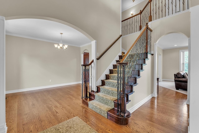 50501 Elmwood Ct, Plymouth, MI 48170 - stairs with arched walkways, wood finished floors, ornamental molding, a chandelier, and a high ceiling