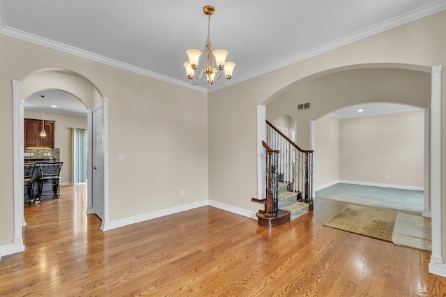 50501 Elmwood Ct, Plymouth, MI 48170 - empty room featuring a chandelier, light wood finished floors, crown molding, arched walkways, and stairs
