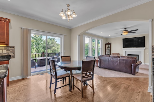 50501 Elmwood Ct, Plymouth, MI 48170 - dining area featuring arched walkways, plenty of natural light, light wood-type flooring, a fireplace, and ornamental molding