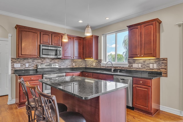 50501 Elmwood Ct, Plymouth, MI 48170 - kitchen with stainless steel appliances, a kitchen bar, decorative light fixtures, a kitchen island, and light wood-style floors