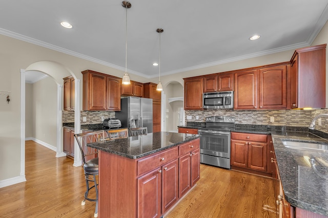 50501 Elmwood Ct, Plymouth, MI 48170 - kitchen with stainless steel appliances, arched walkways, a center island, backsplash, and light wood-type flooring