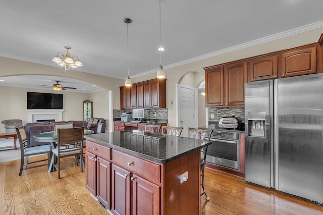 50501 Elmwood Ct, Plymouth, MI 48170 - kitchen featuring appliances with stainless steel finishes, arched walkways, a fireplace, ceiling fan, and a kitchen island