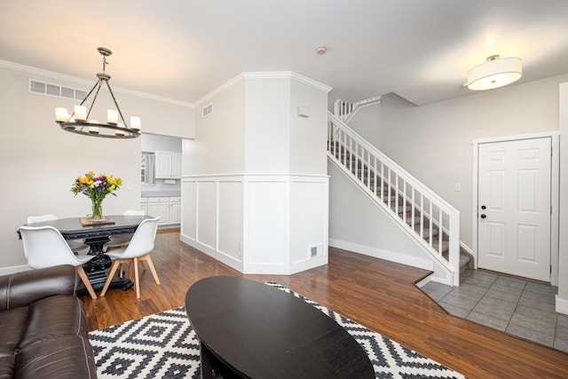 7149 Indian Wells Dr, Ypsilanti, MI 48197 - living room featuring stairway, a chandelier, wood finished floors, crown molding, and a wainscoted wall